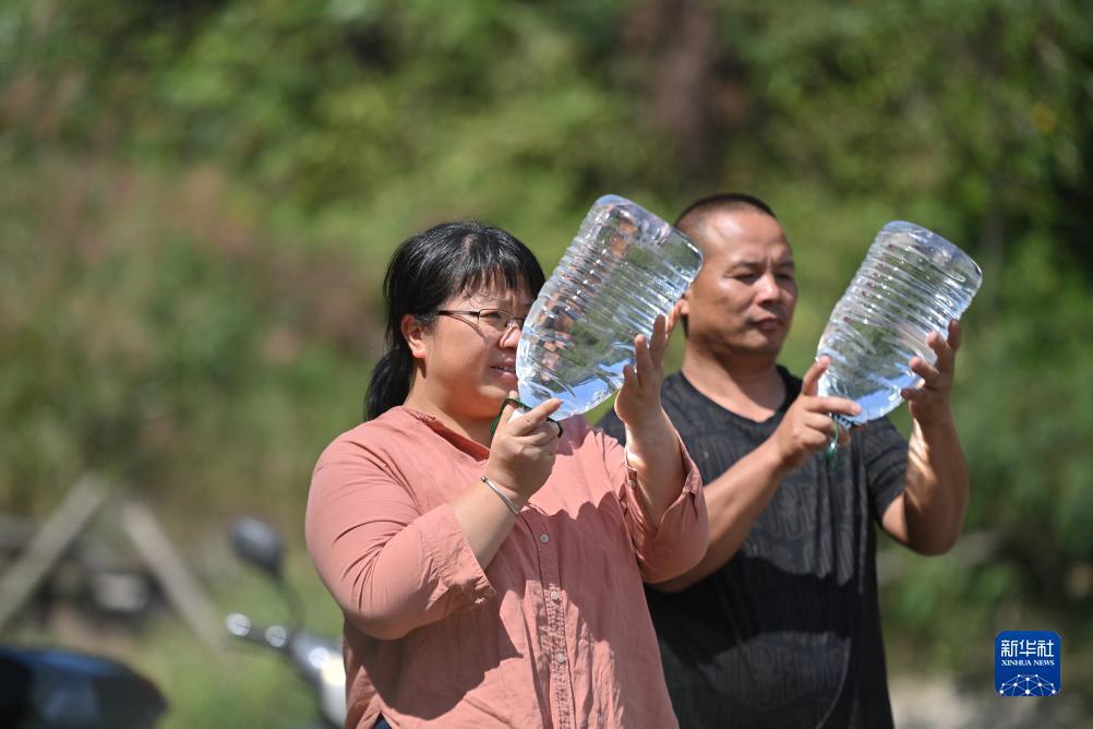 楊寧（左）在查看村民剛剛采集的水樣，為山泉水引水工程做準(zhǔn)備（10月8日攝）。新華社記者 黃孝邦 攝